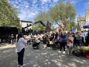 Wide shot of the crowd listening to a speaker welcoming them.