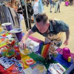 Photo of person trying their luck with the balance a coin on a lemon in a bowl of water trick, on a vibrant coloured DENW stand with lots of fun activities.