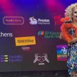 Drag Queen Gypsy Darling on stage at Preston Pride with bright orange ventriloquist monkey.