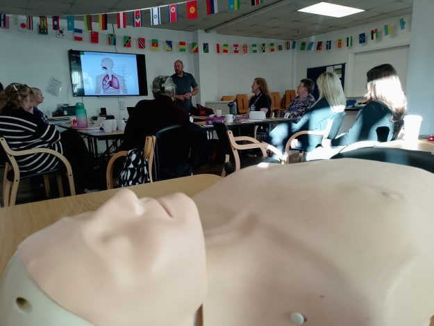 IMG_20251125_135300 Foreground shot of Annie the resuscitation dummy with the group training course in the background.